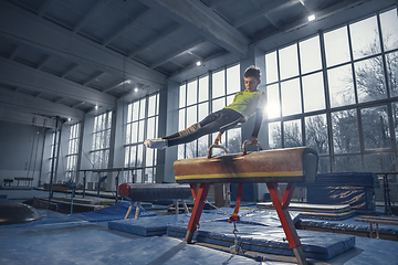 Image showing Little male gymnast training in gym, flexible and active