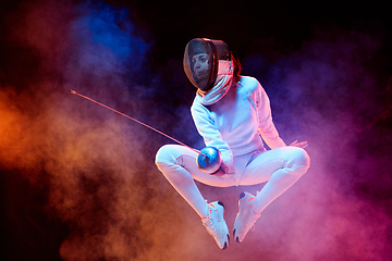 Image showing Teen girl in fencing costume with sword in hand isolated on black background