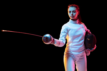 Image showing Teen girl in fencing costume with sword in hand isolated on black background