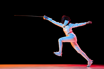 Image showing Teen girl in fencing costume with sword in hand isolated on black background