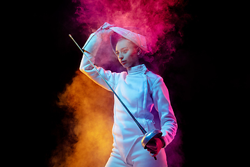 Image showing Teen girl in fencing costume with sword in hand isolated on black background