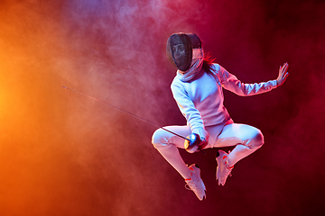 Image showing Teen girl in fencing costume with sword in hand isolated on black background