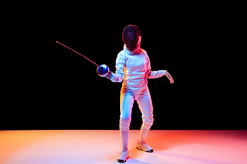 Image showing Teen girl in fencing costume with sword in hand isolated on black background