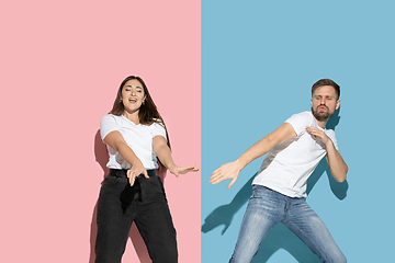 Image showing Young emotional man and woman on pink and blue background