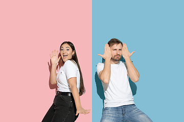 Image showing Young emotional man and woman on pink and blue background