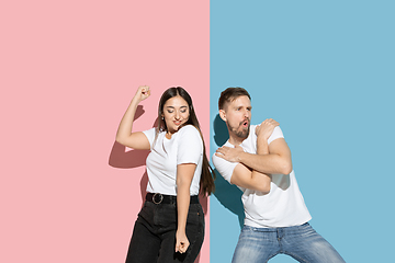 Image showing Young emotional man and woman on pink and blue background