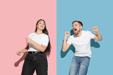 Image showing Young emotional man and woman on pink and blue background