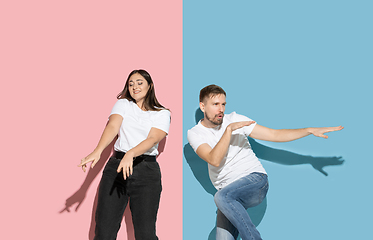 Image showing Young emotional man and woman on pink and blue background