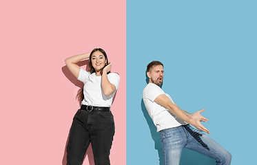 Image showing Young emotional man and woman on pink and blue background