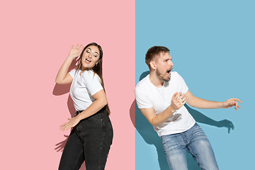 Image showing Young emotional man and woman on pink and blue background