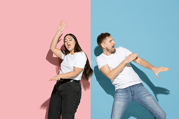 Image showing Young emotional man and woman on pink and blue background