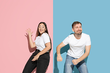 Image showing Young emotional man and woman on pink and blue background