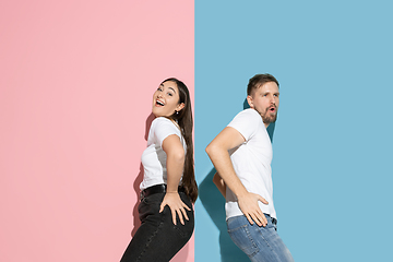 Image showing Young emotional man and woman on pink and blue background