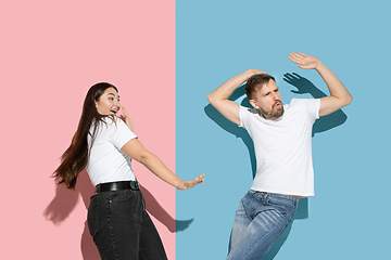 Image showing Young emotional man and woman on pink and blue background