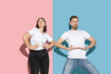 Image showing Young emotional man and woman on pink and blue background