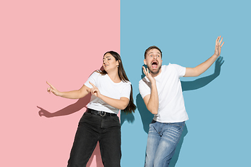 Image showing Young emotional man and woman on pink and blue background