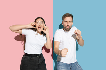 Image showing Young emotional man and woman on pink and blue background