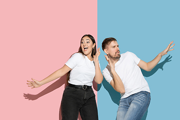 Image showing Young emotional man and woman on pink and blue background