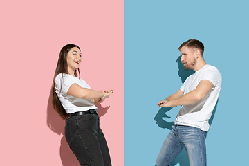 Image showing Young emotional man and woman on pink and blue background