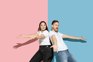 Image showing Young emotional man and woman on pink and blue background