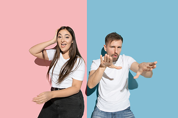 Image showing Young emotional man and woman on pink and blue background