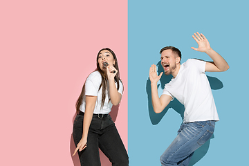 Image showing Young emotional man and woman on pink and blue background