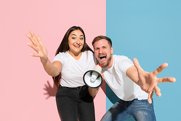 Image showing Young emotional man and woman on pink and blue background