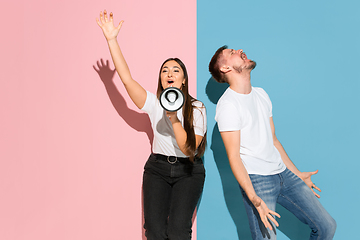 Image showing Young emotional man and woman on pink and blue background