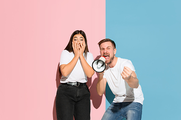 Image showing Young emotional man and woman on pink and blue background