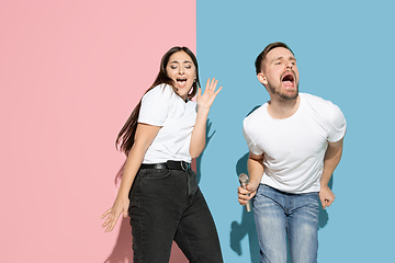 Image showing Young emotional man and woman on pink and blue background