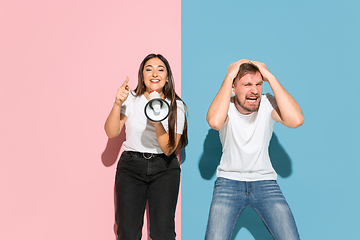 Image showing Young emotional man and woman on pink and blue background