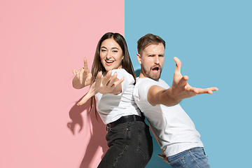 Image showing Young emotional man and woman on pink and blue background