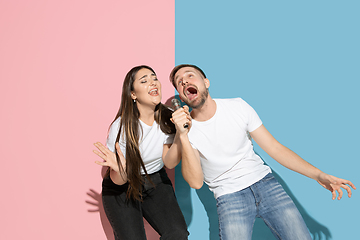 Image showing Young emotional man and woman on pink and blue background