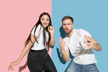 Image showing Young emotional man and woman on pink and blue background