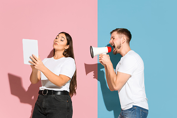 Image showing Young emotional man and woman on pink and blue background