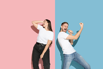 Image showing Young emotional man and woman on pink and blue background