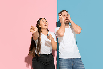 Image showing Young emotional man and woman on pink and blue background