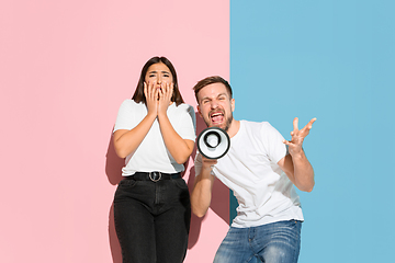 Image showing Young emotional man and woman on pink and blue background