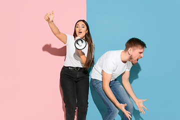 Image showing Young emotional man and woman on pink and blue background