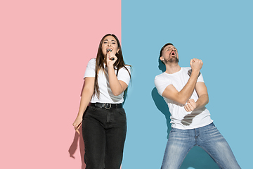 Image showing Young emotional man and woman on pink and blue background