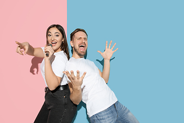 Image showing Young emotional man and woman on pink and blue background