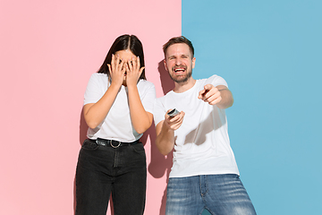 Image showing Young emotional man and woman on pink and blue background