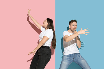 Image showing Young emotional man and woman on pink and blue background