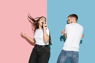 Image showing Young emotional man and woman on pink and blue background