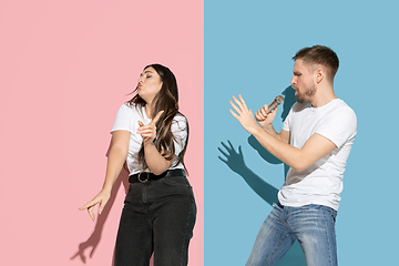 Image showing Young emotional man and woman on pink and blue background