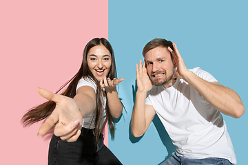 Image showing Young emotional man and woman on pink and blue background