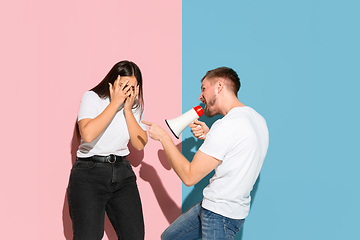 Image showing Young emotional man and woman on pink and blue background