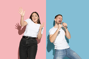 Image showing Young emotional man and woman on pink and blue background