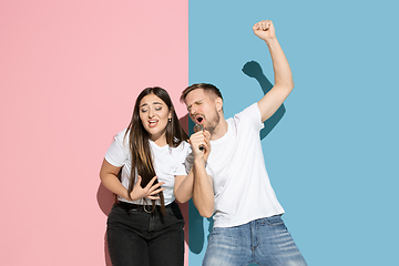 Image showing Young emotional man and woman on pink and blue background