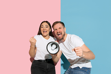 Image showing Young emotional man and woman on pink and blue background